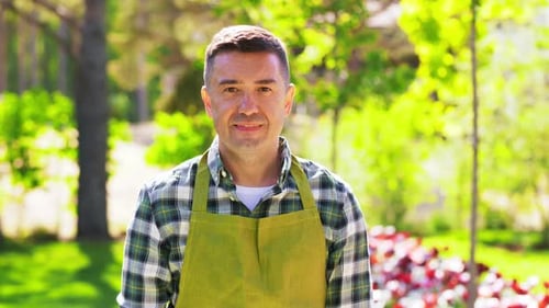 Gardening and People Concept - Happy Smiling Middle-Aged Man in Apron Showing