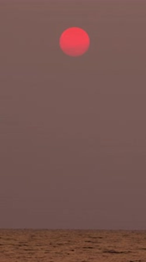 Timelapse of dramatic sunset with orange sky in a cloudy day at a sea.