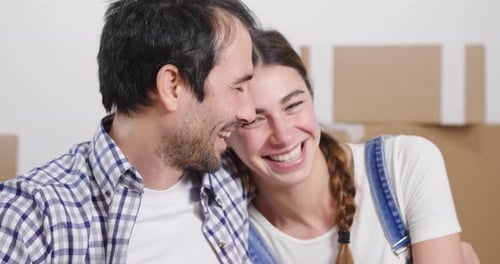 Portrait of a couple in love seated on the floor and they just bought a house and are moving. The