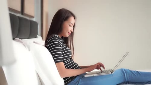 Woman Working on Laptop Computer in Bed