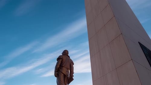 Time lapse of statue and stone obelisk with statue on top with smooth cloud movement
