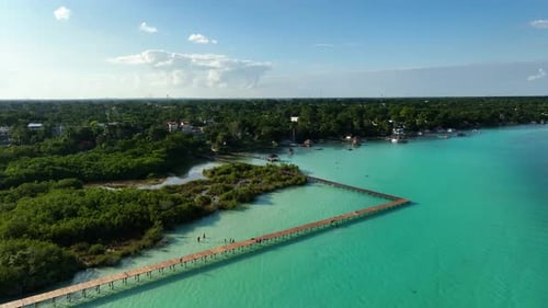 Personnes marchant sur les quais de la zone naturelle protégée Parque Laguna de Bacalar, sous le soleil du Mexique