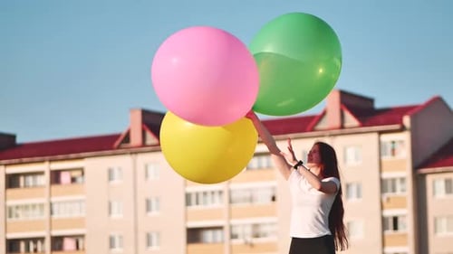 A Girl Happily Poses with Large with Colorful Balloons in the City