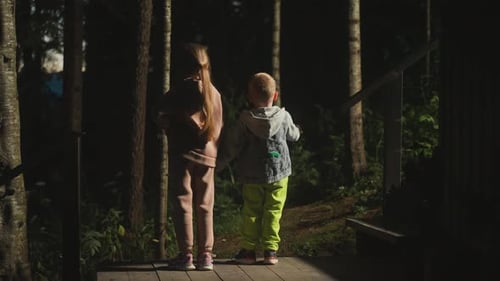 Children on Ground Among Wild Dark Forest at Twilight
