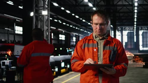 Employee in Protective Gear Checks Equipment in a Fabrication Workshop