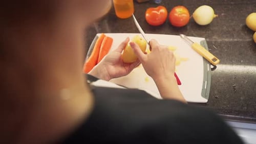 Female hands peeling potatoes in the kitchen cutting board