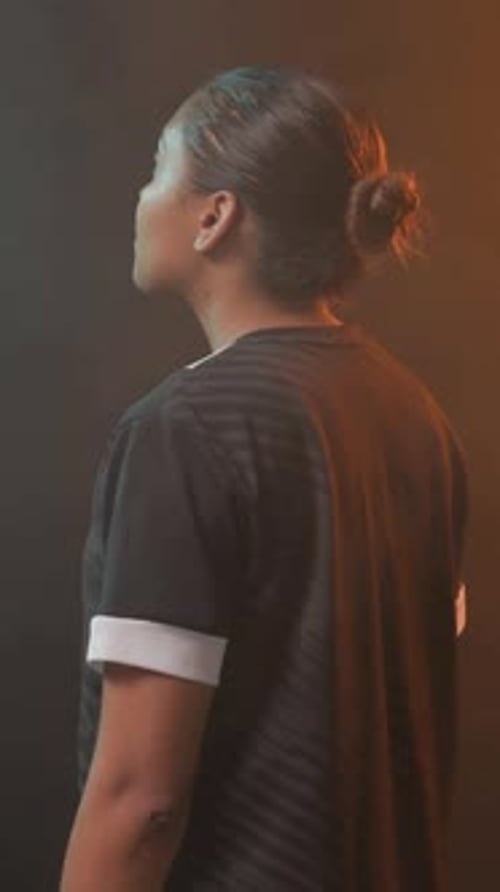 Vidéo verticale : Femme se tournant vers la caméra en studio pour un gros plan, haut noir, poignets blancs, chignon