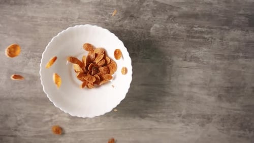 Trockene Cornflakes aus Hartweizen fallen von oben in die Schüssel und an der Seite befindet sich Kopierraum