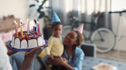 Family celebrating birthday with cake and candles indoors