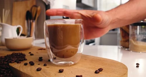 Hand Grabs Glass of Coffee in Bright Kitchen