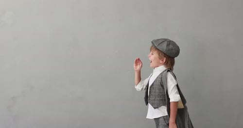 Child Dressed in Vintage Outfit Posing Against Gray Wall