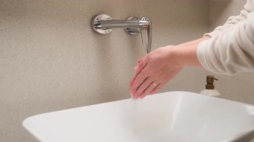 Woman Washing Hands in Modern Bathroom Sink