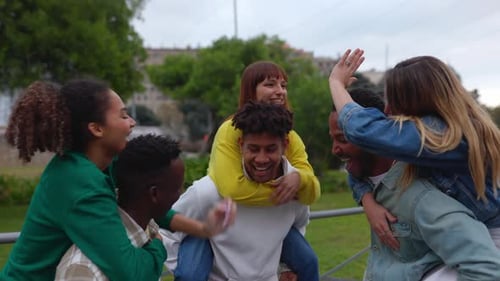 Six Friends Enjoying Piggyback Rides in Urban Park