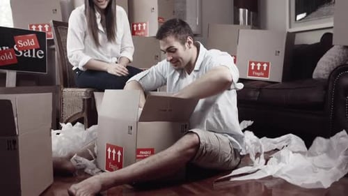 Couple Unpacking Moving Boxes in Living Room