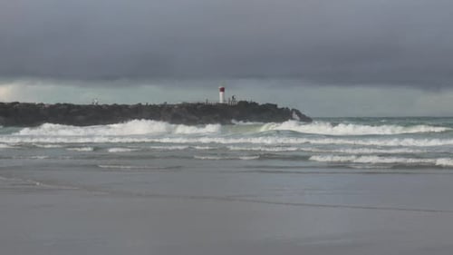 Lighthouse rocky coastline Australia, grey storm clouds agitated ocean waves