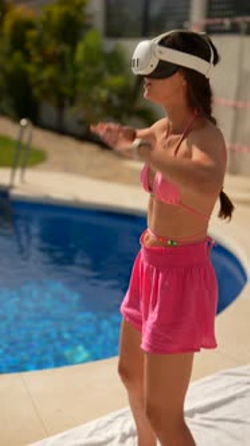 A Woman in Pink Shorts and Sportswear Using Virtual Reality for a Workout By a Pool on a Sunny Day