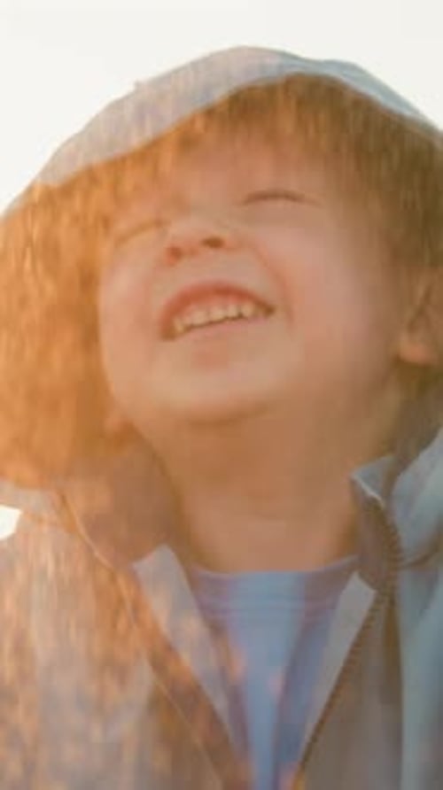 Boy Smiles in the Rain in Blue Hooded Raincoat