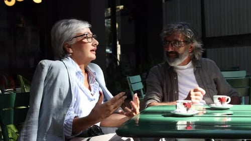 Two People Chatting Over Coffee at Outdoor Cafe