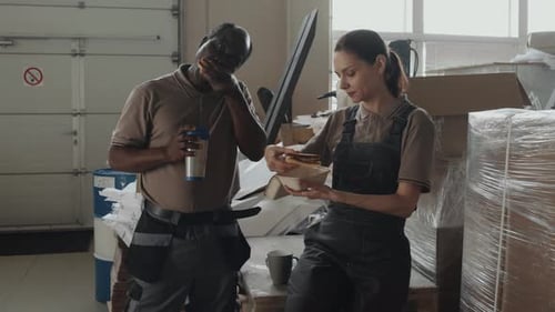Two Workers Having Lunch In Warehouse