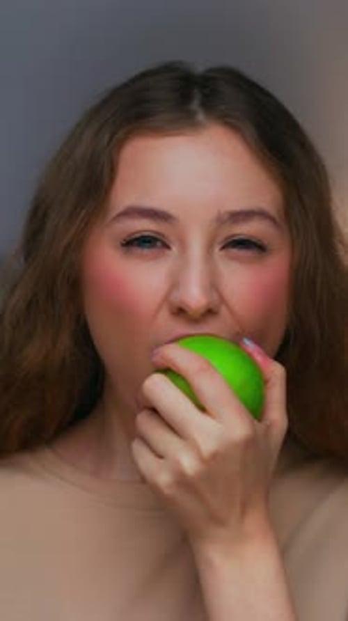 Portrait of Young Woman Eating Healthy Food of Green Apple and Looking at Camera