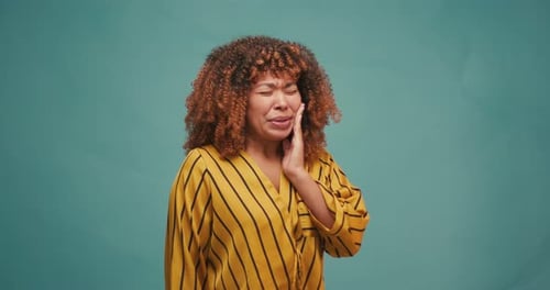 Young Hispanic Woman Feeling Teeth Pain on Blue Background