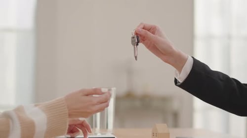 Close-up of a real estate agent in a black suit handing over house keys