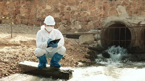 Scientist Testing Water Quality Near Sewage Pipe