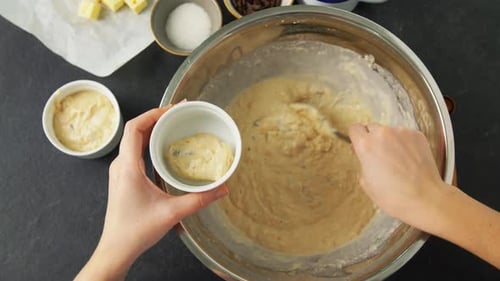 Woman's hands carefully filling muffin molds with batter in slow motion