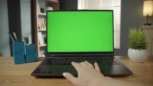 Hand Operating a Laptop Featuring a Chroma Key Green Screen Suitable for Compositing While Working