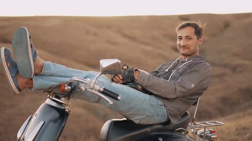 Man Relaxing on Scooter in Field at Sunset