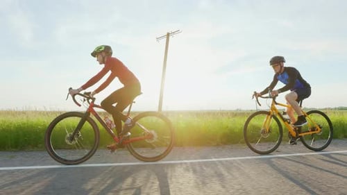 Two Cyclists Riding Bike on Asphalt Road Outdoors