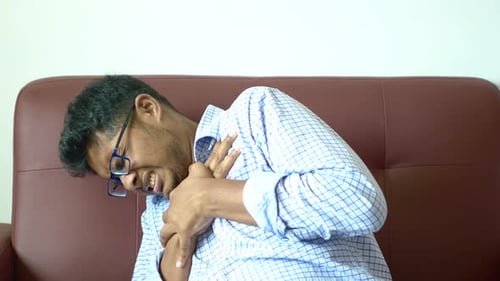 Hombre joven que sufre dolor en el corazón y sostiene el pecho con la mano