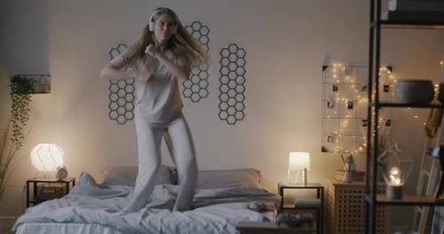 Energetic Woman Dancing on Bed with Headphones