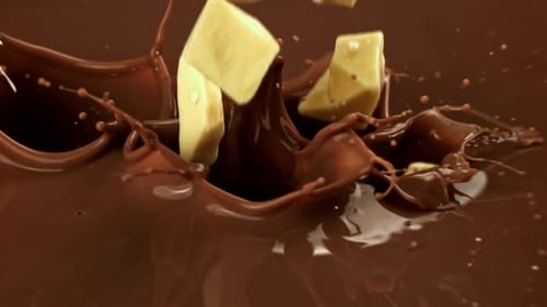 Chocolate Cámara lenta El chocolate blanco cae en un líquido de leche filmado con una cámara de alta velocidad en