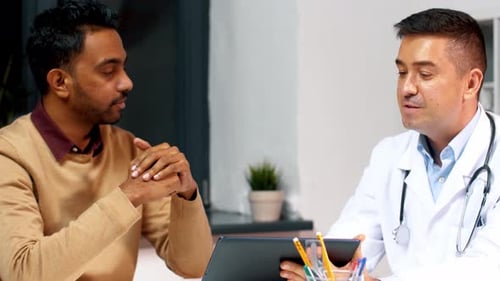 Doctor discussing healthcare app with patient at hospital in medical office