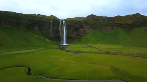 Picturesque Waterfall Scenery with Grassy Valley and People