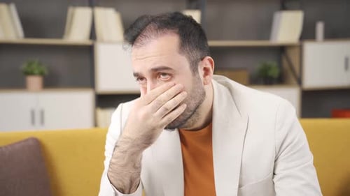 Man Sitting on Couch Looking Sad and Worried