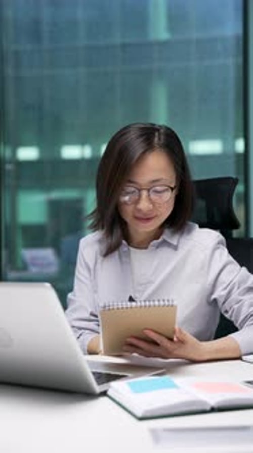 Woman Working at Desk Taking Notes in Office