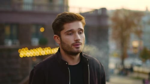 Portrait d'un beau mec qui souffle de la fumée d'une cigarette électronique à l'extérieur. Gros plan Hipster Man