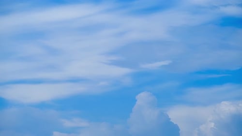 The wind was blowing the fluffy white clouds across the bright blue sky, creating a mesmerizing moti