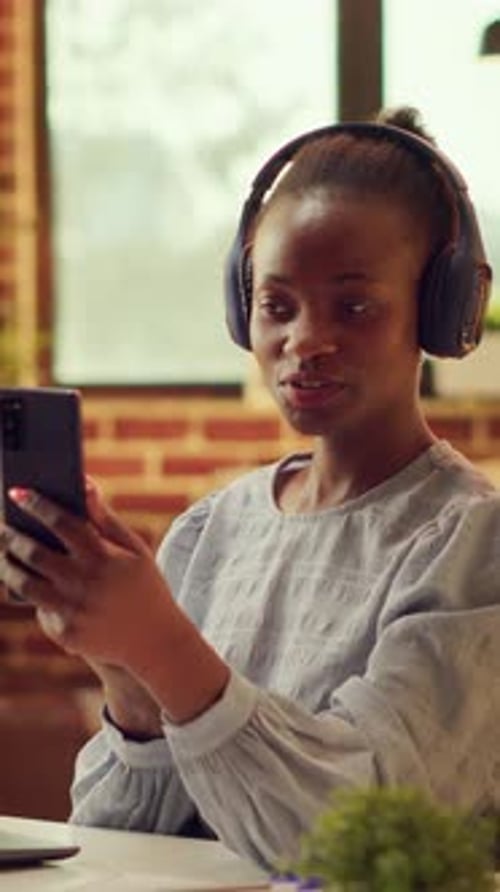 Woman With Headphones Using Phone at Desk