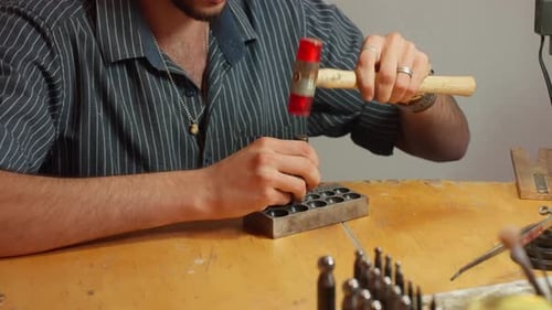 Crafting metal objects in a workshop with a hammer and metal mold during an afternoon session
