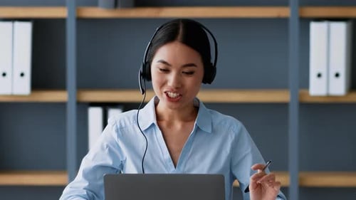Young Asian Woman Engages in Online Business Meeting at Coworking Office