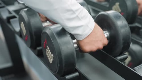 Close Up Hand Reaching for Dumbbell From Gym Rack for Workout