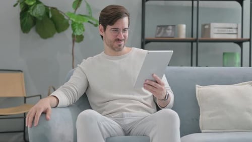 Man Video Chatting on Tablet From Home Couch