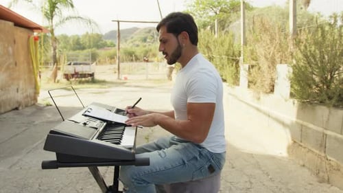 Young Adult Writing Music at Keyboard