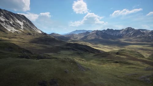 Hillside Overgrown with Dry Grass Against the Backdrop of Snowcapped Mountains