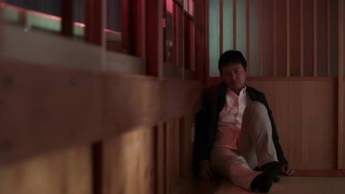 Man Sitting Against Wall Looking at Camera Indoors