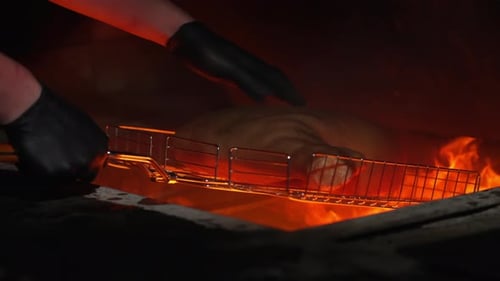 The Cook Puts the Meat on the Grill for Roasting on the Fire