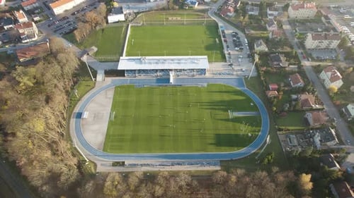 Aerial establishing shot of the soccer field during the football match with few spectators due to th